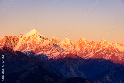 Panoramic view during sunset over snow cladded Panchchuli peaks falls in great Himalayan mountain range from small hamlet Munsiyari, Kumaon region, Uttarakhand, India.