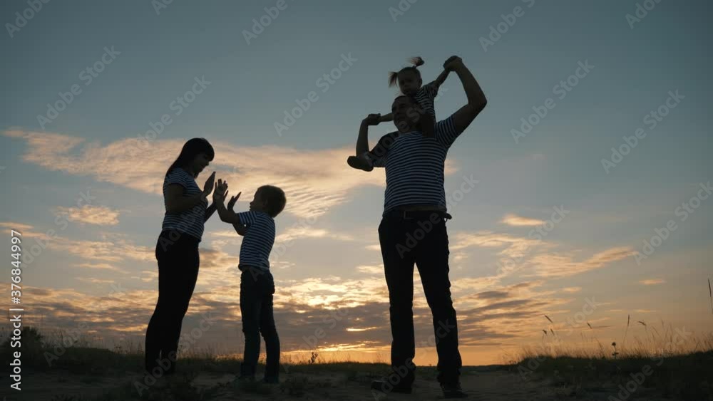 custom made wallpaper toronto digitalSilhouette of a happy family in the evening in the park. Mom plays with her son and touches his palms. The father is carrying a little daughter on his shoulders. Family outdoors.