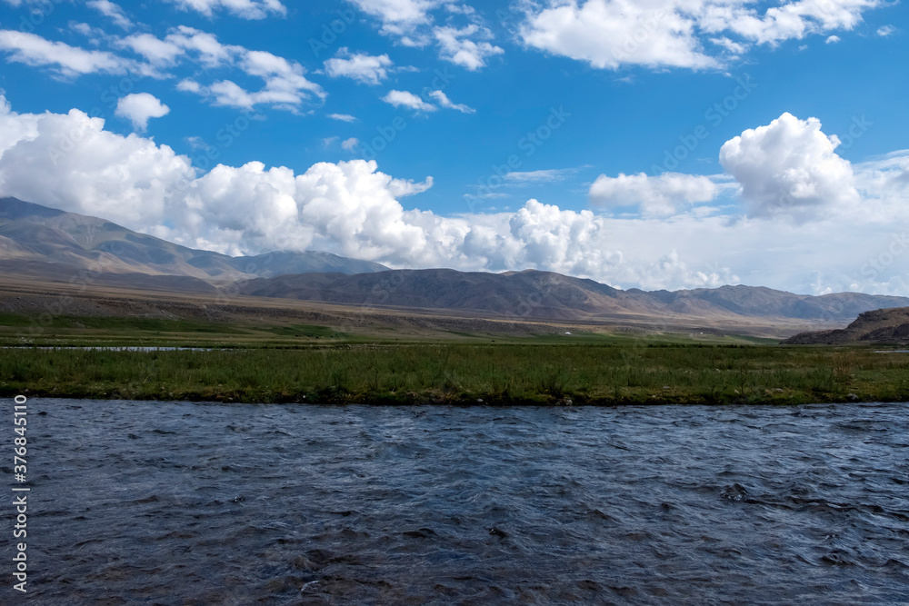 Beautiful river with mountains and clouds background. Summer river valley landscape. Summer nature landscape. Summer season. Adventure travel. Summer vacation. Blue sky. Borokhudzir line, Kazakhstan. Beautiful river with mountains and clouds background. Summer river valley landscape. Summer nature landscape. Summer season. Adventure travel. Summer vacation. Blue sky. Borokhudzir line, Kazakhstan.