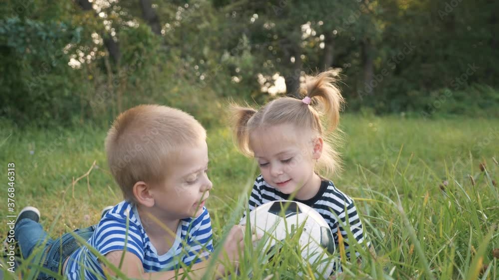 Happy family in the park on the grass. Children play with a ball in the park.The kid learns to play in a team. Happy, sweet family is dreaming. Dream concept. Teamwork of kid in the park. Kid's dream. Happy family in the park on the grass. Children play with a ball in the park.The kid learns to play in a team. Happy, sweet family is dreaming. Dream concept. Teamwork of kid in the park. Kid's dream.