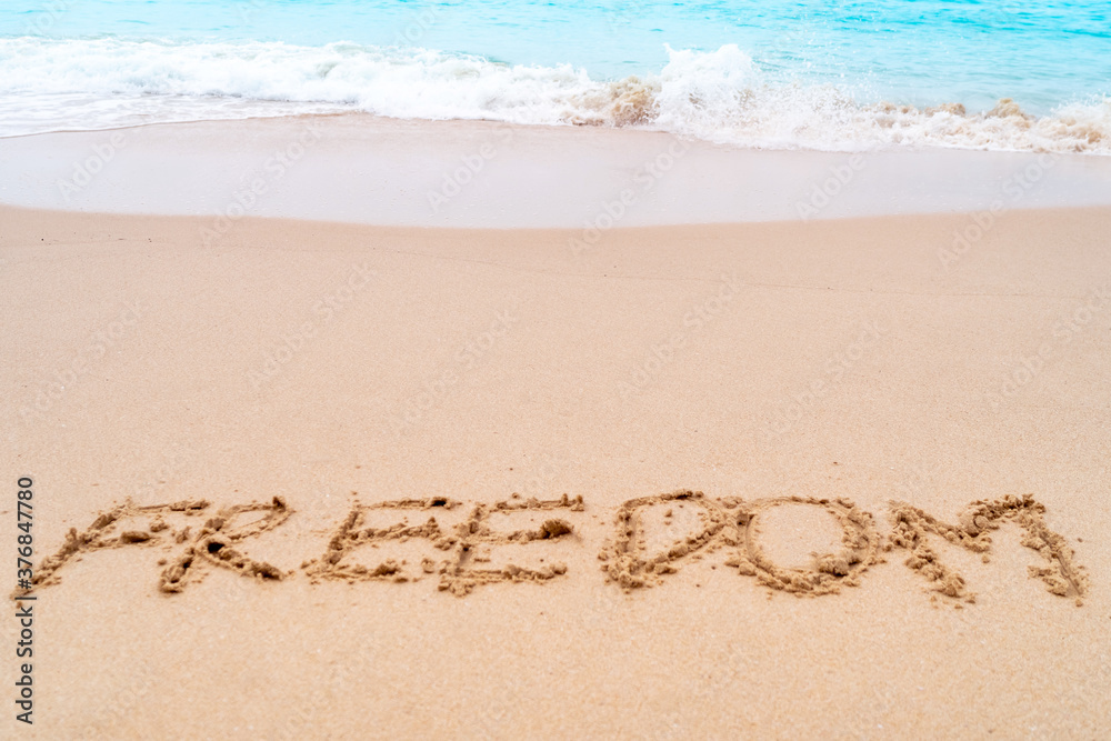 Freedom word hand drawn on sand summer beach. Freedom word hand drawn on sand summer beach.