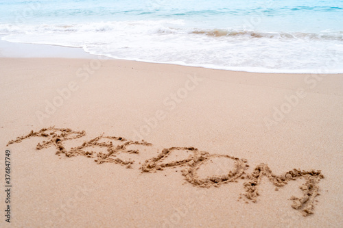 Freedom word hand drawn on sand summer beach.