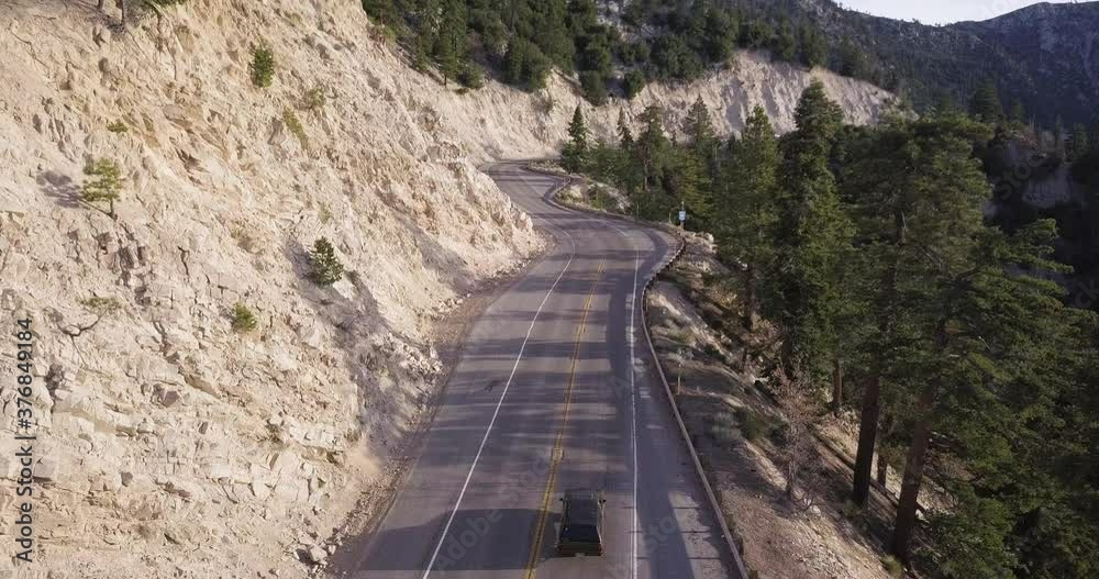 Black truck travels on Highway 18 in California with white cliffs left and valley right, tracking aerial shot Black truck travels on Highway 18 in California with white cliffs left and valley right, tracking aerial shot