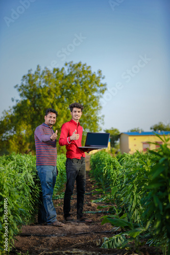 Young indian farmer with agronomist at field