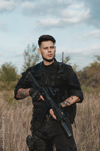 Young soldier in black uniform with an assault rifle.