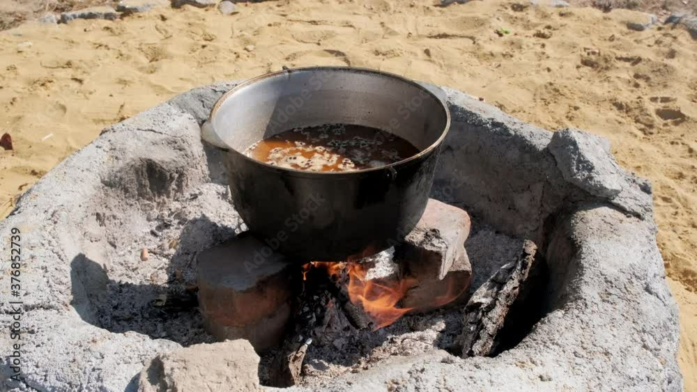 Cooking pilaf in a large cauldron over an open fire. Close-up. Cooking pilaf in a large cauldron over an open fire. Close-up.