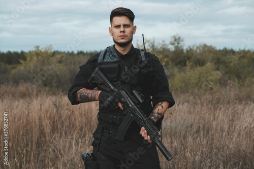 Young soldier in black uniform with an assault rifle.