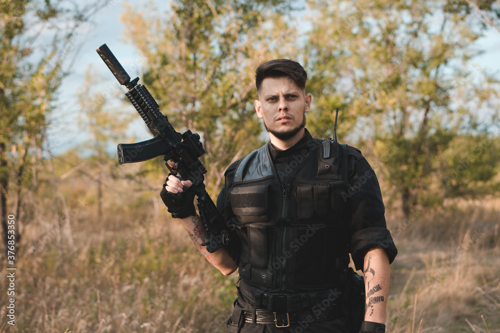 Fototapeta premium Young soldier in black uniform with an assault rifle.