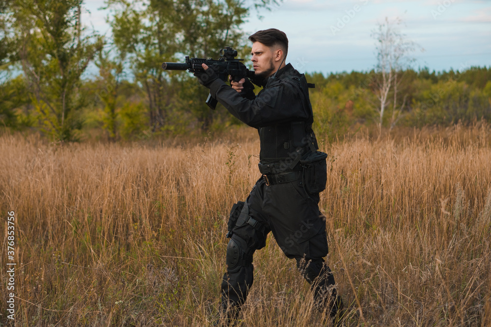 Young soldier in black uniform aiming an assault rifle. Young soldier in black uniform aiming an assault rifle.