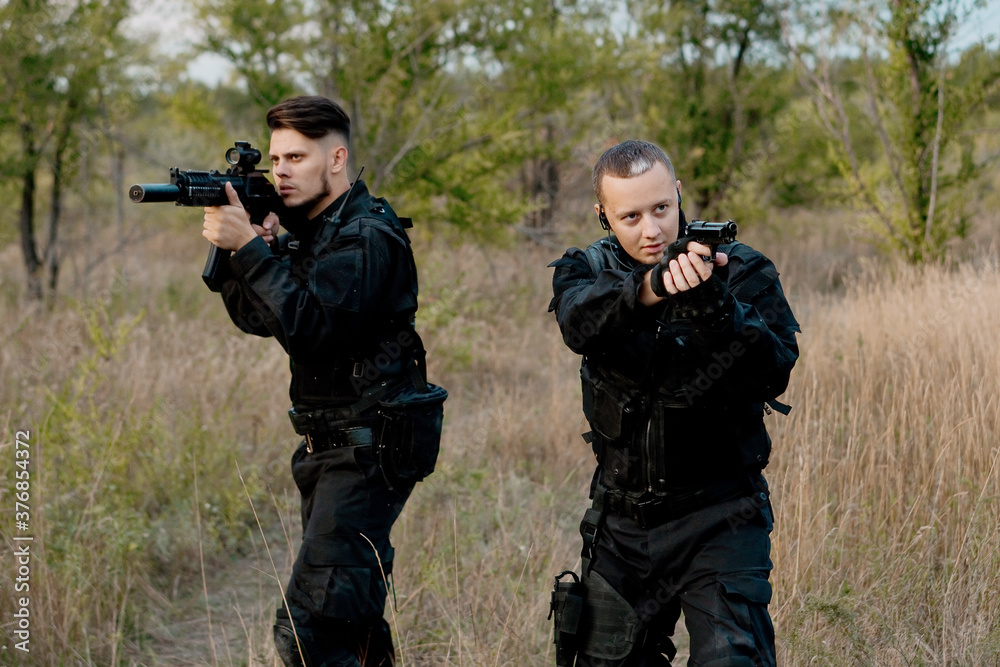Two special forces soldiers in black uniform aiming in different directions. Two special forces soldiers in black uniform aiming in different directions.