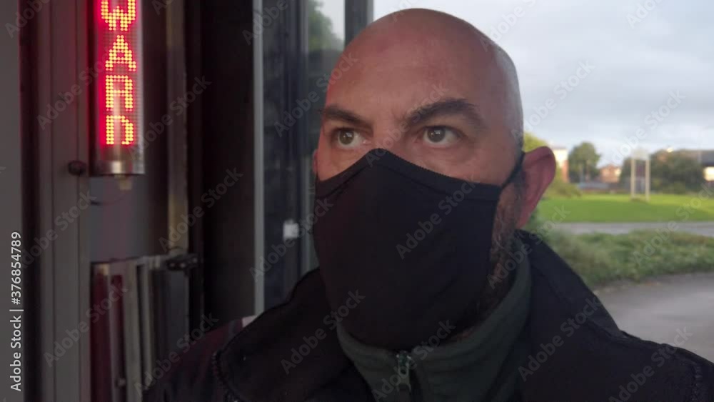 Male opening car wash workplace wearing PPE corona virus face mask at stop sign looking ahead Male opening car wash workplace wearing PPE corona virus face mask at stop sign looking ahead