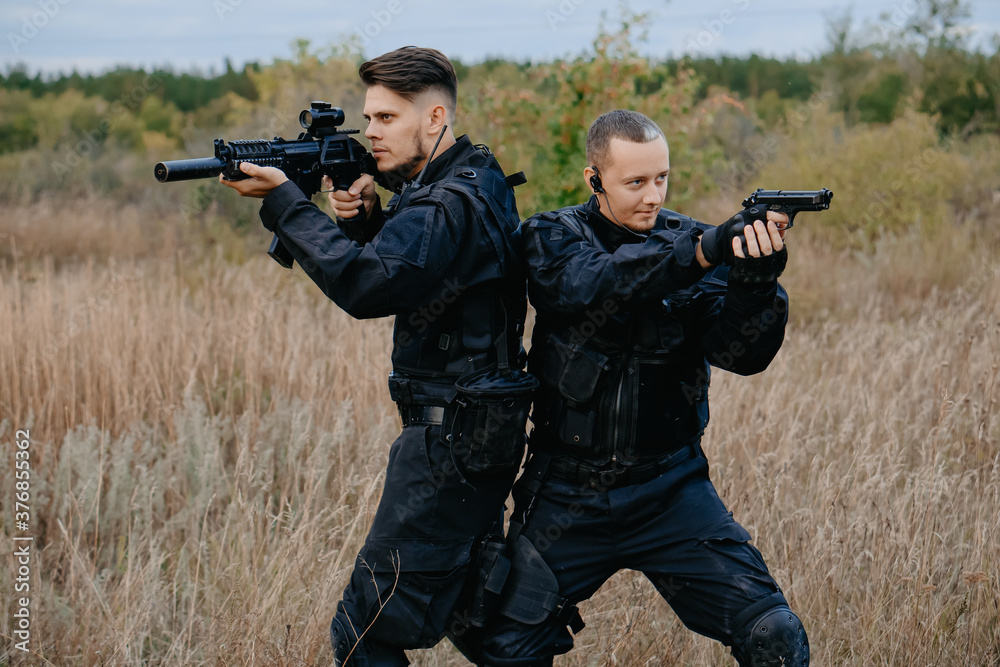 Fototapeta premium Two special forces soldiers in black uniform aiming in different directions.