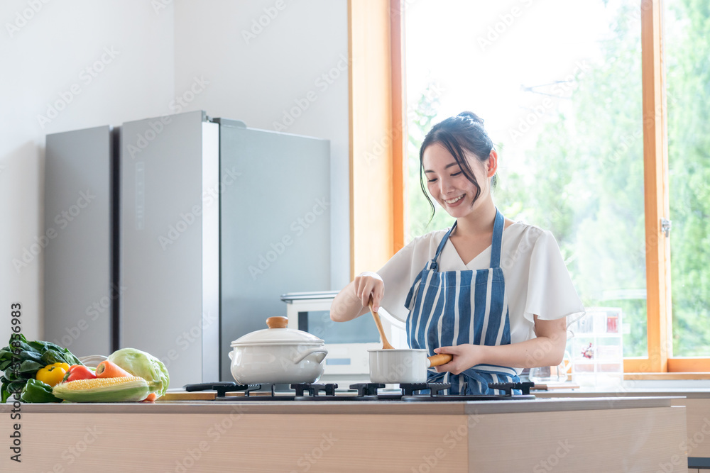 キッチンで料理する若い女性