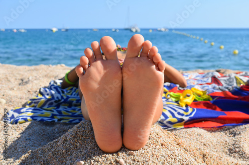 Woman lying in the sun with her feet facing the camera and her head towards the sea  vacation.