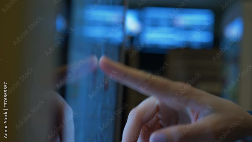 woman consumer uses self-service payment terminal touching screen by finger on blurred background in light store extreme closeup