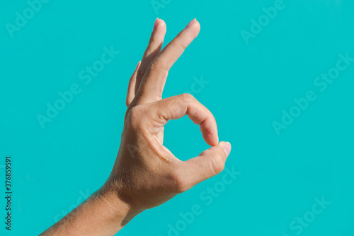 Female hand on a blue background. Two hands sign ok.  one hand with fingers