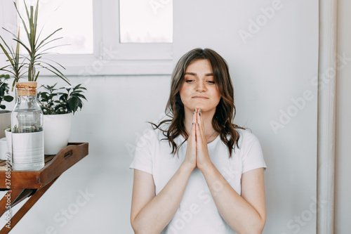 Happy woman in a white t-shirt prays, relaxes and does yoga