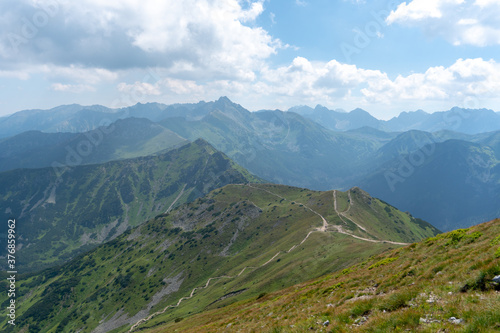Long and curved hiking trails through the red peaks in Tatra Mountains in Poland during hot summer day.
