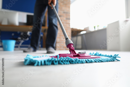 Billede på lærred Man with mop washes floor in office