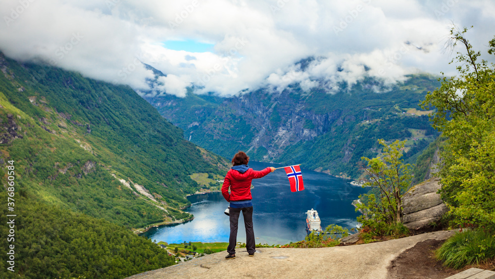 Tourist over Geirangerfjord holds norwegian flag