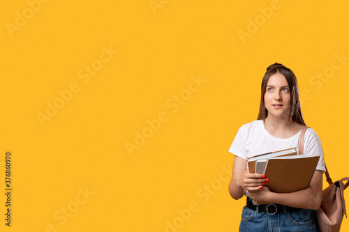 Back to school. Smart student. Curious young woman with backpack and notebooks isolated on orange copy space. Education and training course. Think idea
