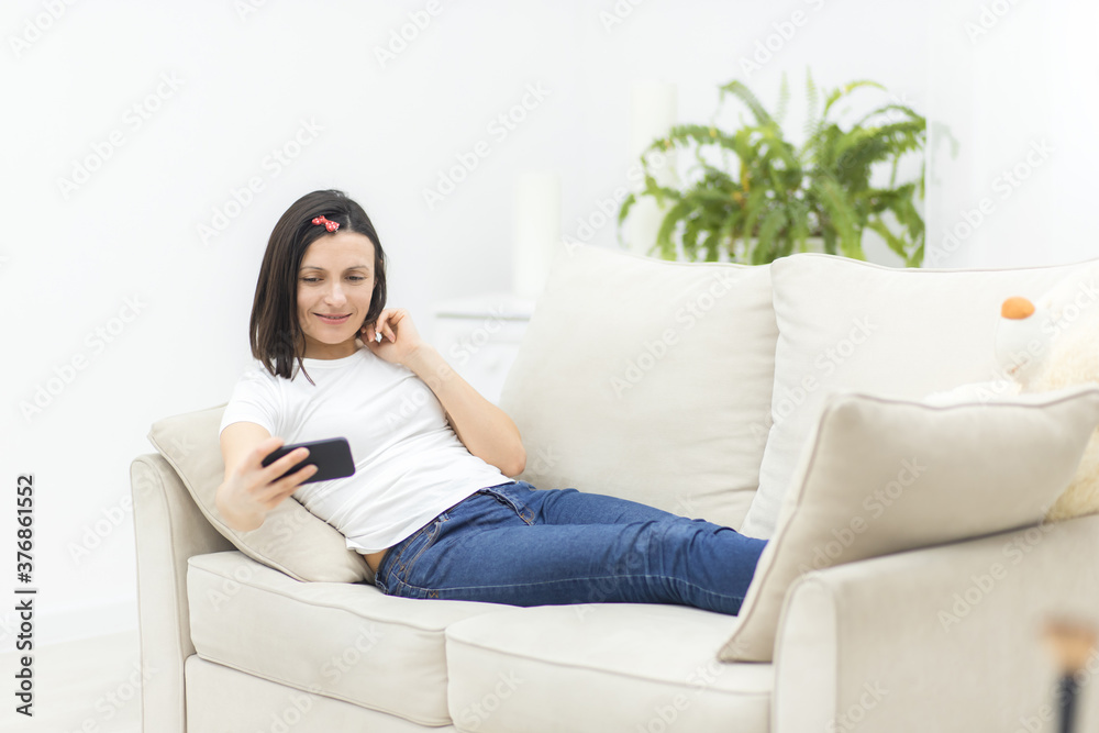 Photo of smiling woman lying on sofa making selfie. Photo of smiling woman lying on sofa making selfie.