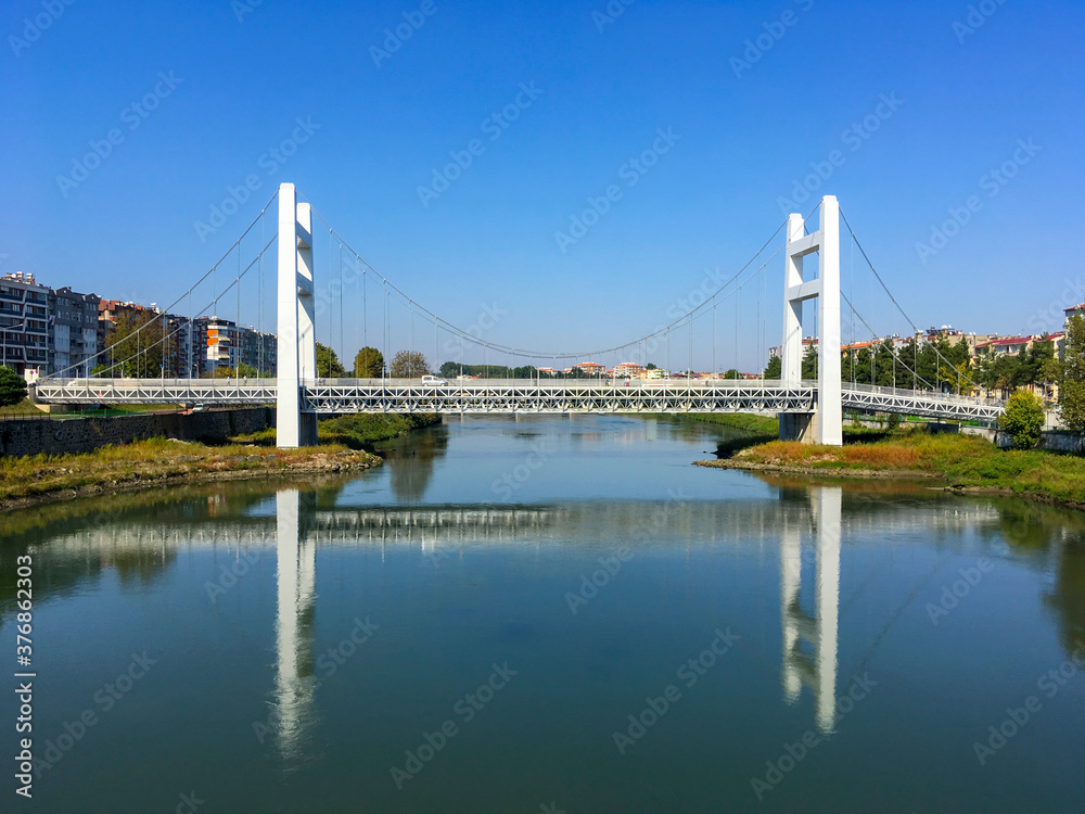Obraz premium The white bridge in district of Carsamba, in city of Samsun, Turkey is looking like Bogazici Bridge in Istanbul. Nice reflection of bridge over Yesilirmak River.