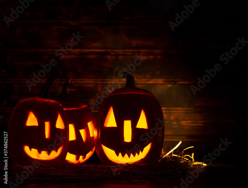 Halloween iluminated pumpkins on wooden background. Halloween background with copy space.