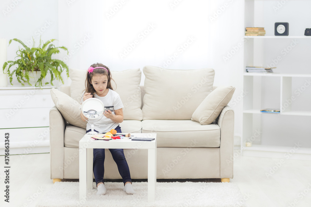 Photo of small girl painting her eyes looking in the mirror. Photo of small girl painting her eyes looking in the mirror.