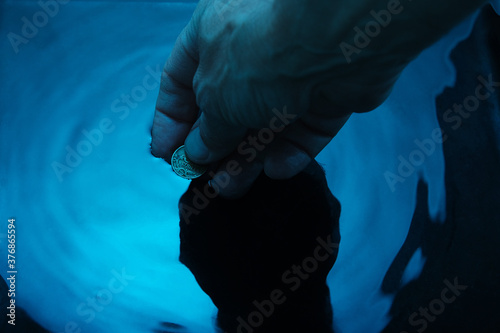 hand pulls a coin from blue liquid