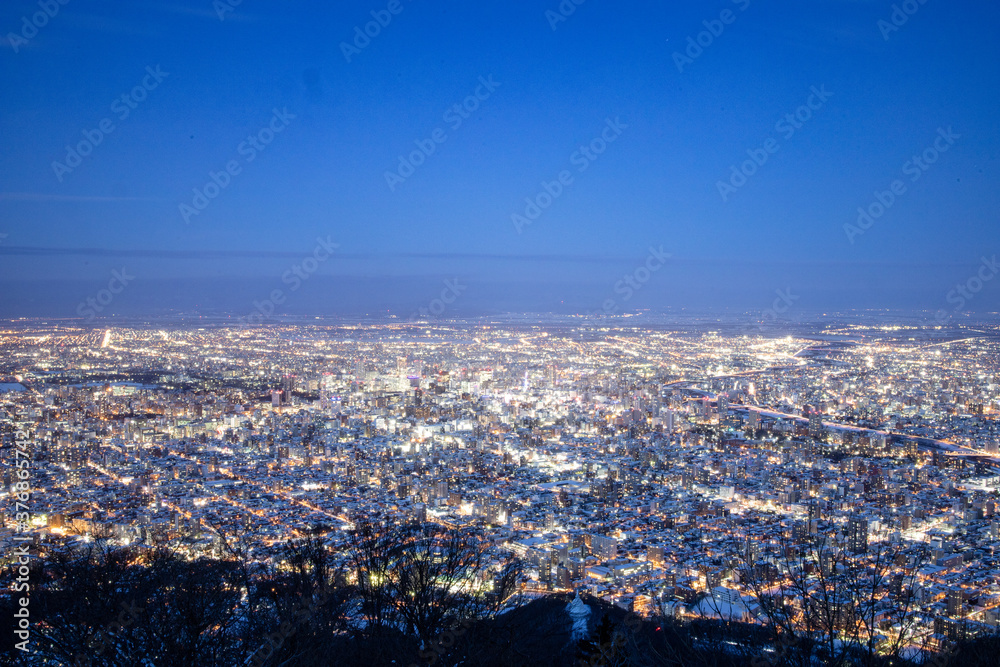 View from top of Mt. Moiwa in Sapporo city, Hokkaido, Japan during winter with night cityscape blur background.