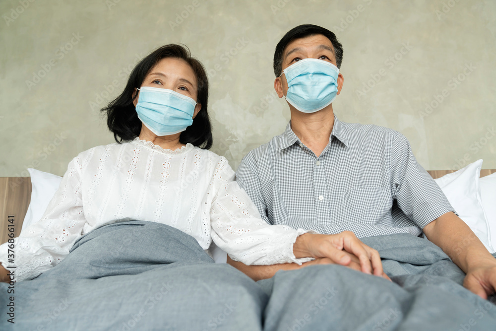 Portrait of Asian couple elder senior old male and female wearing face medical mask. pandemic coronavirus disease quarantine in home. Covid-19 outbreak prevention concept.