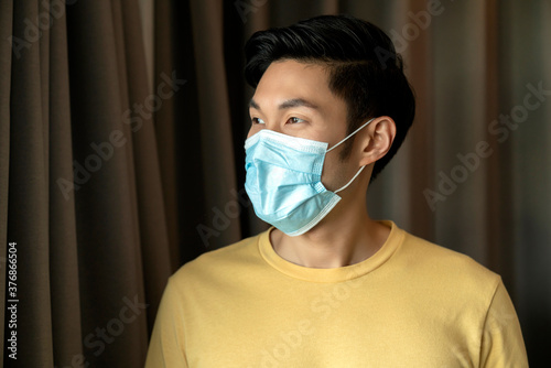 Portrait of Asian young male wear face medical mask. pandemic coronavirus disease quarantine in home. Covid-19 outbreak prevention concept.