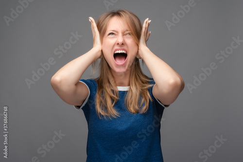 Angry Blonde shut ears with hands and screams. Human emotions, facial expression concept