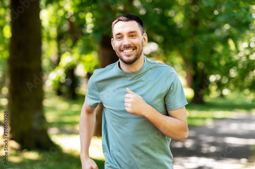 Fototapeta Naklejka Na Ścianę i Meble -  fitness, sport and healthy lifestyle concept - happy young man running at summer park