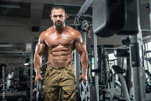 Attractive tall muscular bodybuilder doing heavy deadlifts in moder fitness center. © romanolebedev