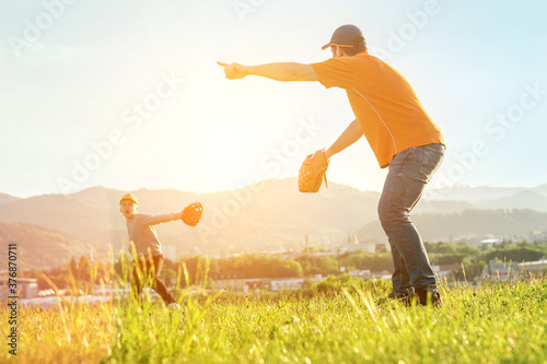Father and son playing in baseball. Playful Man teaching Boy baseballs exercise outdoors in sunny day at public park. Family sports weekend. Father's day. 