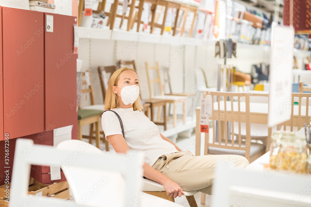 New normal during covid epidemic. Caucasian woman shopping at retail furniture and home accessories store wearing protective medical face mask to prevent spreading of corona virus. New normal during covid epidemic. Caucasian woman shopping at retail furniture and home accessories store wearing protective medical face mask to prevent spreading of corona virus.