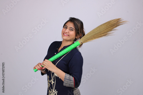 Photography Young asian woman of indian origin with a sweeping broom
