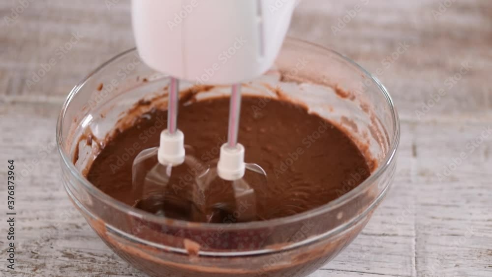 Mixing chocolate dough or batter for baking cakes, cookies, pastry. Mixer beating chocolate in bowl. Mixing chocolate dough or batter for baking cakes, cookies, pastry. Mixer beating chocolate in bowl.