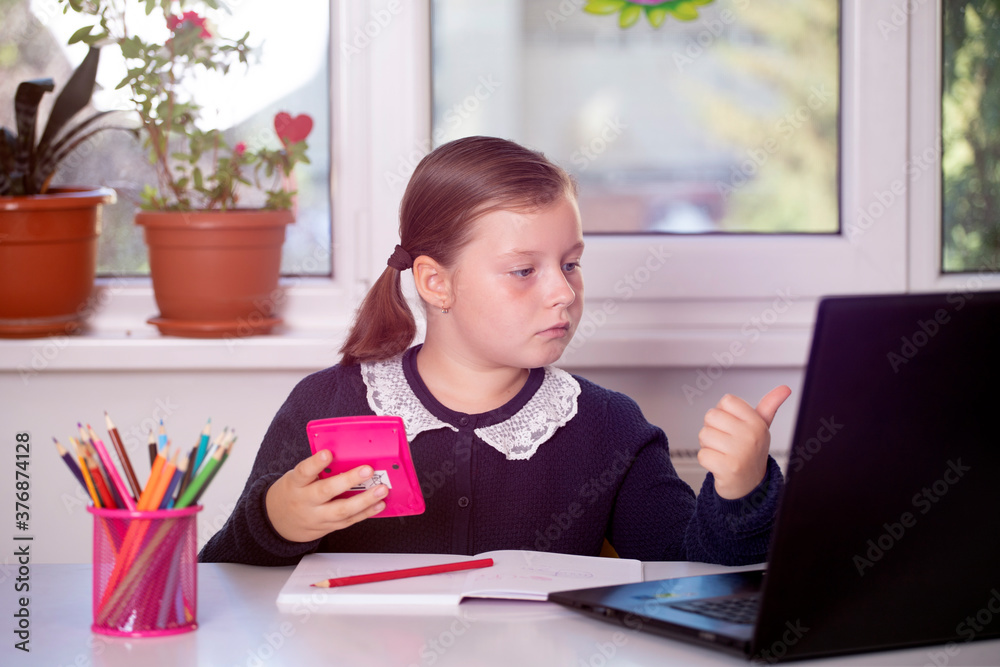 Study online with video call teacher. Young girl learn online and looking at laptop at home.Social distancing. Study online with video call teacher. Young girl learn online and looking at laptop at home.Social distancing.