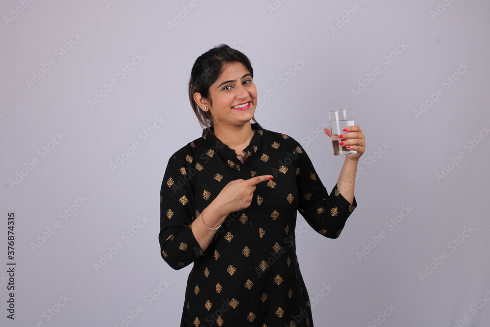 Indian lady/women holding plain glass of water, isolated over white background Indian lady/women holding plain glass of water, isolated over white background