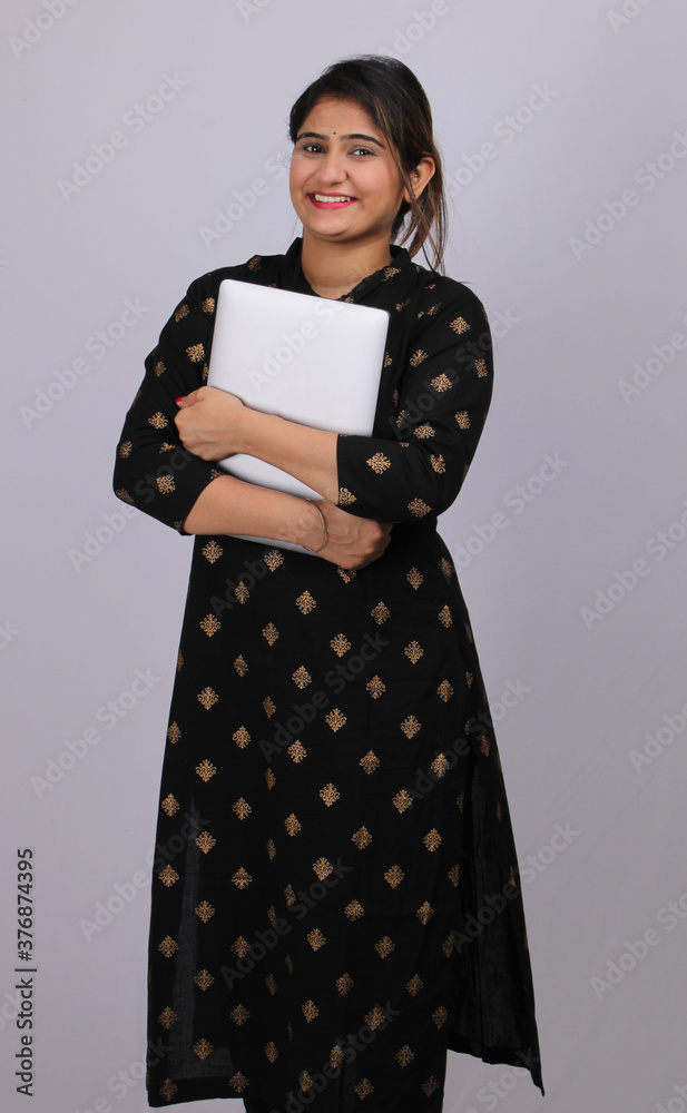 Indian young woman holding grey color laptop in hand. Indian young woman holding grey color laptop in hand.