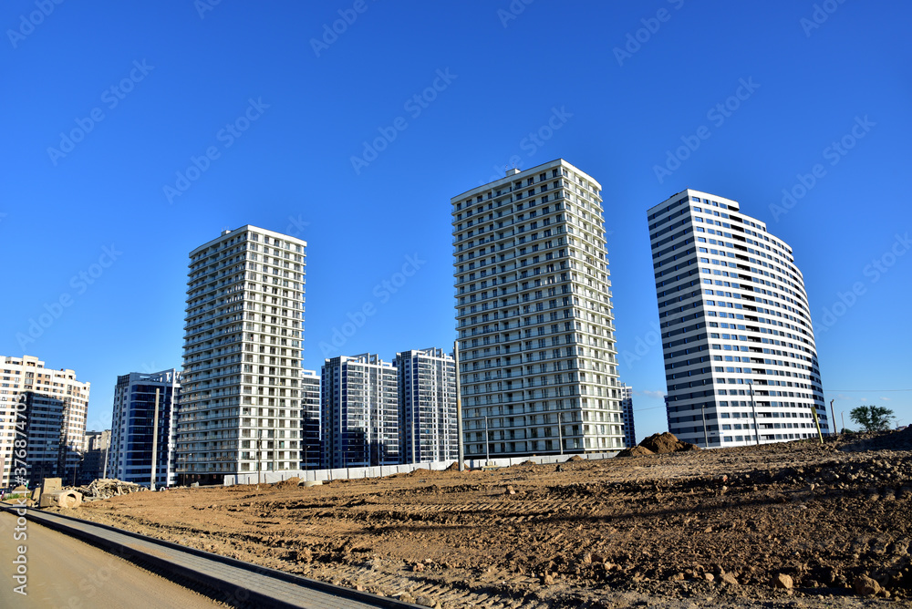 View of a large construction site with tall residential buildings and skyscrapers. Road and road junction construction. Laying of concrete sewer pipes View of a large construction site with tall residential buildings and skyscrapers. Road and road junction construction. Laying of concrete sewer pipes