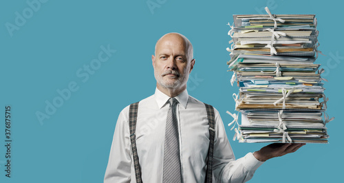 Obraz na plátně Confident businessman holding a pile of paperwork with one hand