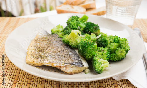 dish of fried dorado fish fillet with boiled broccoli