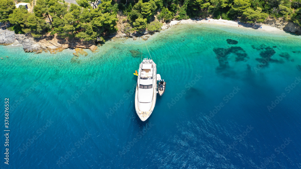 Aerial drone photo of yacht anchored in famous crystal clear bay and turquoise beach of Panormos, Skopelos island, Sporades, Greece