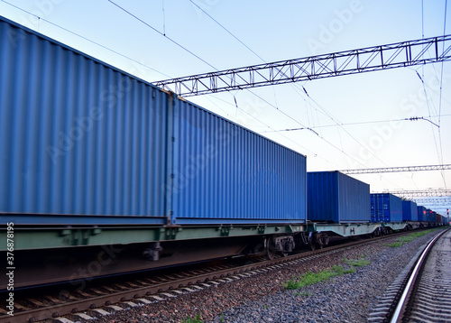 Cargo Containers Transportation On Freight Train By Railway. Intermodal Container On Train Car. Rail Freight Shipping Logistics Concept. Soft focus, possible granularity. Object in motion