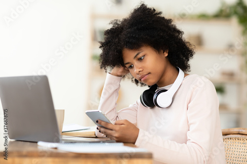 African Girl Using Smartphone And Laptop Watching Lecture At Home