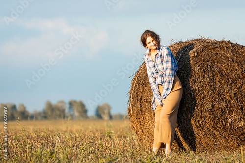 Pretty fresh  young woman  posing outdoors in field  and wearing in stylish clothes in the background a haystack  field  .Concept of summer  holidays at village  and live style